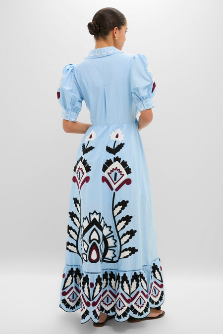 Woman in a Blue Artisanal Short Sleeve Maxi Dress, featuring classic puffed sleeves and an effortlessly full skirt with fun, high-end floral and geometric motifs.