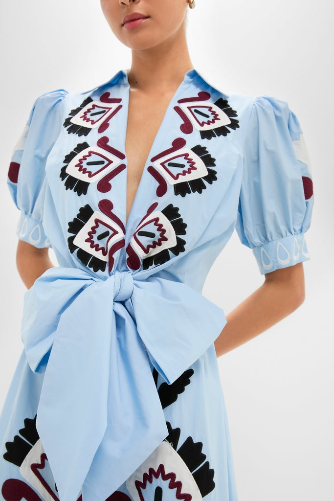 Effortlessly elegant, the Blue Artisanal Short Sleeve Maxi Dress features puffy sleeves, geometric embroidery, and a sash bow, embodying Tuckernuck's classic, high-end, and fun style.