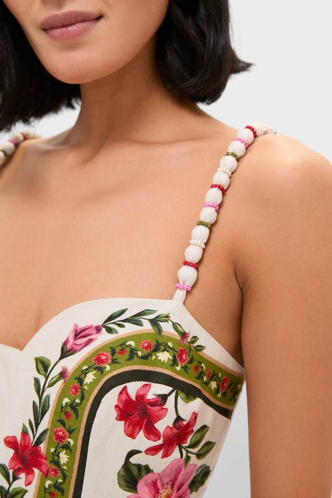 Woman wearing Wonder Rio Sand Sleeveless Maxi Jumpsuit with beaded straps; a classic, effortless high-end piece showcasing floral print and sustainable linen fabric.