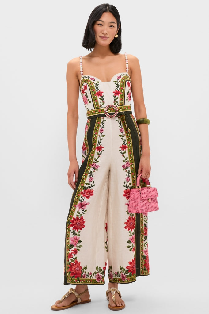 Model wearing the classic Wonder Rio Sand Sleeveless Maxi Jumpsuit with floral panels, beaded straps, and a matching belt, styled with fun, high-end accessories.