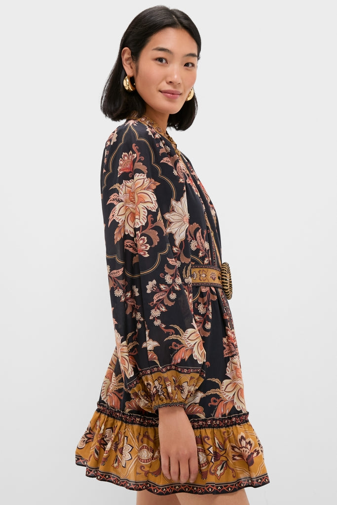 Young woman in profile wearing the Majestic Garden Black Mini Dress; a classic, high-end bohemian-style with an effortless cinched waist, ruffled hem, and fun, billowy sleeves.