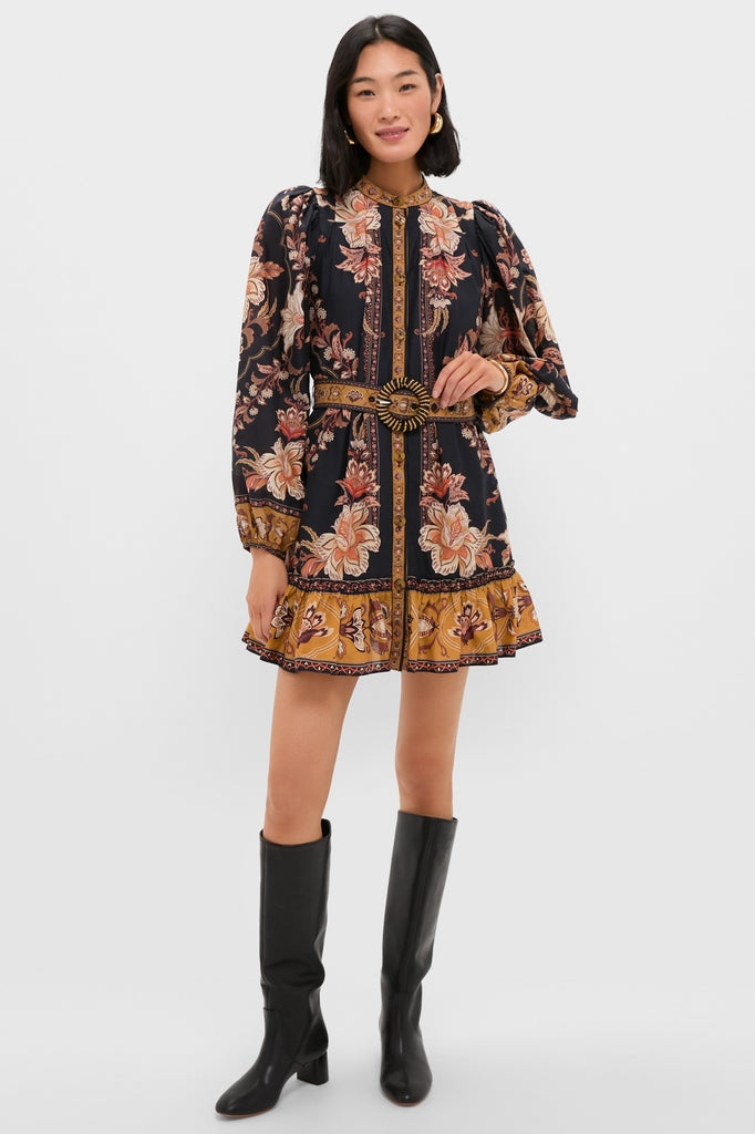 Model wearing Majestic Garden Black Mini Dress with floral print, ruffled hem, matching belt, paired with black knee-high boots and gold hoop earrings for an effortless, classic look.