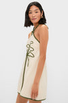 Young woman in the Sand Coconut Sleeveless Mini Dress, featuring a classic, effortless design with an olive-green cord detail, embodying fun and high-end style.