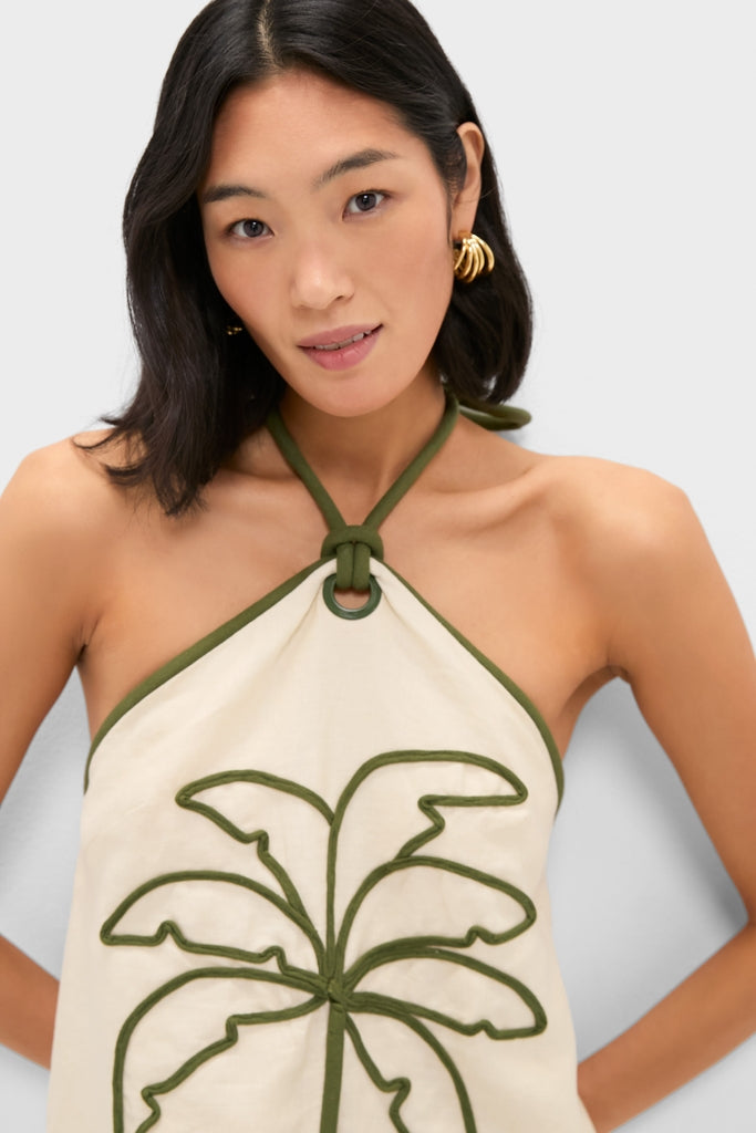 Young woman models the Sand Coconut Sleeveless Mini Dress, featuring a classic halter-neck with a botanical motif, embodying an effortless and high-end style.