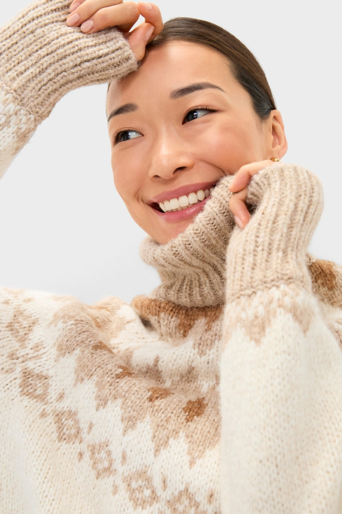 Young woman smiles in a classic, high-end Ivory Camel Estelle Fair Isle Turtleneck, showcasing its effortless style and cozy, fun design with elegant details.