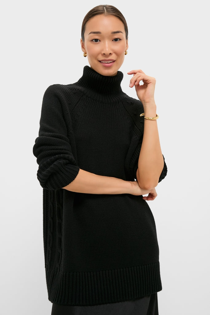 Person in Black Louisa Turtleneck Sweater with cable-knit sides, ribbed cuffs, accessorized with gold bangle. Classic and effortless style reflecting Tuckernuck's high-end, fun ethos.