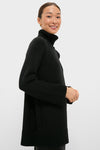 Young woman wearing classic Black Louisa Turtleneck Sweater with high-end cable-knit detailing, ribbed cuffs, and foldover neck, embodying effortless, fun sophistication.