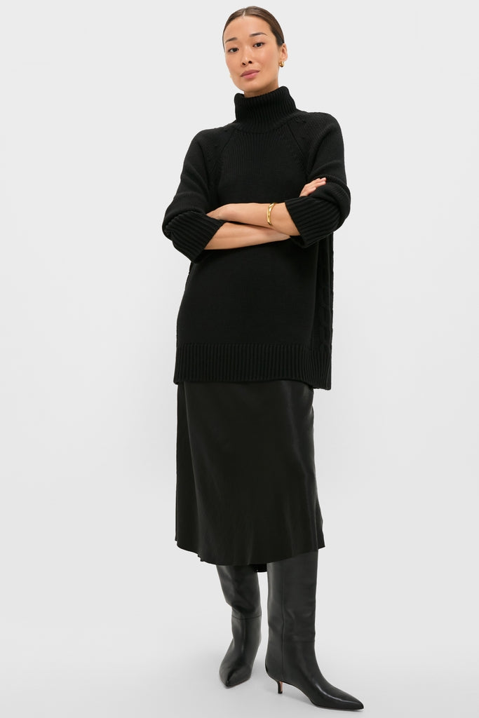 Woman wearing the classic Black Louisa Turtleneck Sweater, featuring an effortless foldover neck and side cable-knit details, embodying high-end, fun sophistication.
