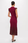 Woman wearing the Plum Shimmer Knit Midi Dress, a classic, effortless burgundy midi with ruffled cap sleeves and pleated skirt, styled with black sling-back heels.