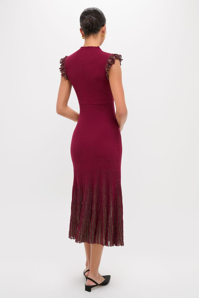 Woman wearing the Plum Shimmer Knit Midi Dress, a classic, effortless burgundy midi with ruffled cap sleeves and pleated skirt, styled with black sling-back heels.