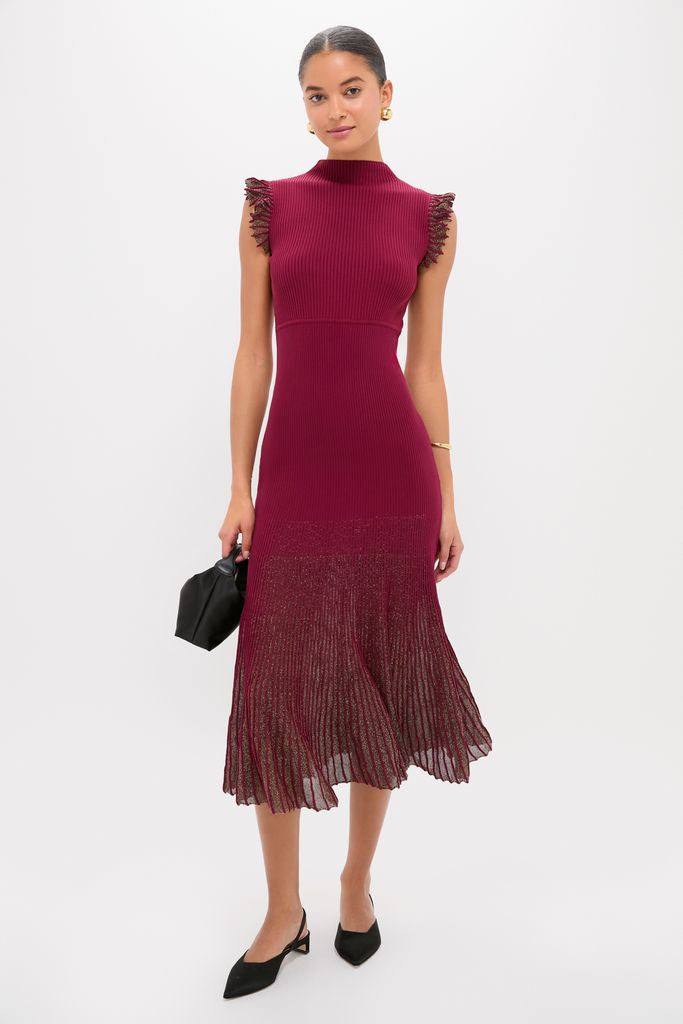 Woman modeling the Plum Shimmer Knit Midi Dress, featuring a classic ribbed top and an effortless sheer pleated skirt, styled with a high-end black handbag and fun gold jewelry.