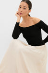Young woman in a classic, effortless Black and Ivory Off Shoulder Maxi Dress, showcasing a fitted bodice and flowing skirt, embodying high-end, fun style.