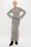 Black and Ivory Striped Maxi Dress, featuring a classic, form-fitting design with long sleeves and an ankle-length skirt, exudes effortless, high-end style. Paired with pointed-toe black ankle boots.