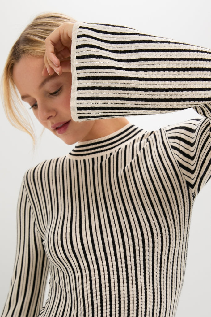 Model wearing a classic Black and Ivory Striped Maxi Dress with a mock-neck and flared cuffs, embodying an effortless and high-end style.