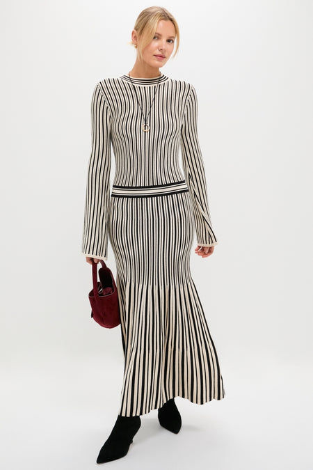 Model wearing the Black and Ivory Striped Maxi Dress, featuring a classic ribbed, long-sleeve top and flared skirt, styled with an effortless, high-end touch.