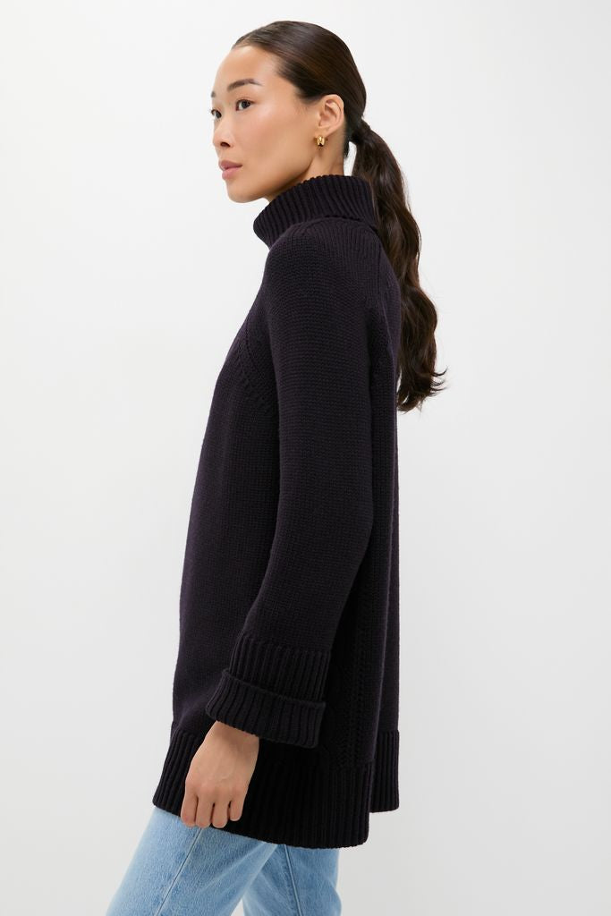 Woman in profile wearing the classic Navy Louisa Turtleneck Sweater with ribbed cuffs, showcasing a foldover neck and intricate side cable-knit detailing for an effortless, high-end look.