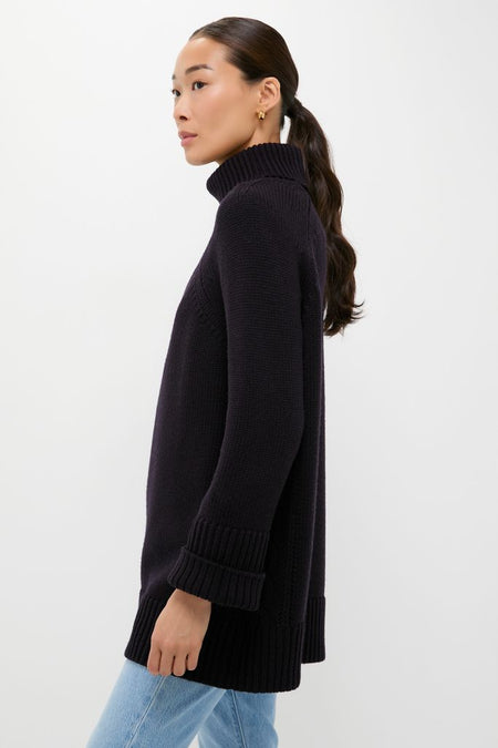 Woman in profile wearing the classic Navy Louisa Turtleneck Sweater with ribbed cuffs, showcasing a foldover neck and intricate side cable-knit detailing for an effortless, high-end look.