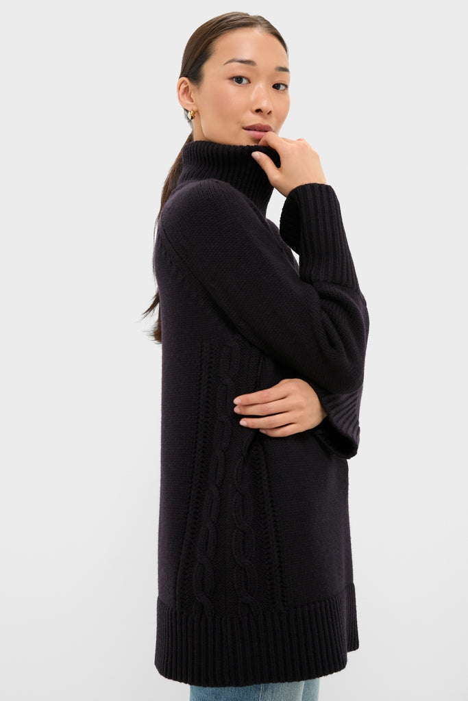 Woman in profile wearing the classic Navy Louisa Turtleneck Sweater with cable-knit details and ribbed finishes, embodying an effortless, high-end style with small hoop earrings and light-wash jeans.