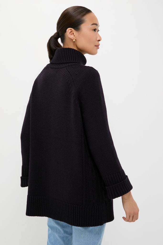 Person in classic, high-end Navy Louisa Turtleneck Sweater with foldover neck, paired with light jeans and gold hoops, exuding effortless, fun sophistication.