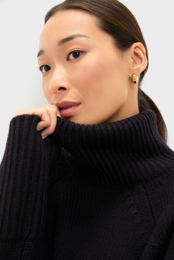 Young woman in a classic Navy Louisa Turtleneck Sweater, showcasing its effortless high-end style with ribbed texture and a foldover neck, exuding calm confidence.