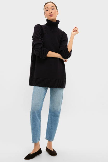 Woman wearing the classic Navy Louisa Turtleneck Sweater, an effortless, high-end piece with a foldover neck and side cable-knit detailing, paired with light blue jeans.