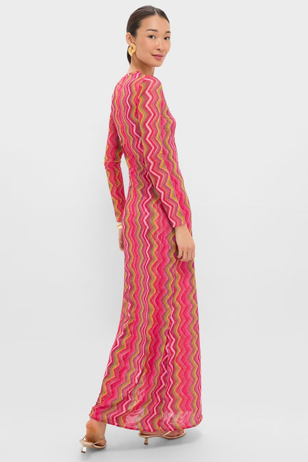 Model in profile wearing the Electric Wave Pink Scarlet Maxi Dress, featuring a classic, bold chevron pattern, styled effortlessly with heeled sandals and statement earrings.