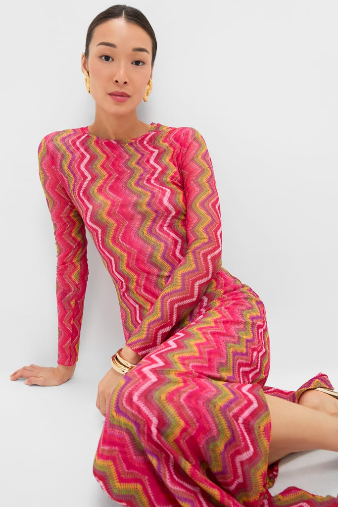 Model wearing the Electric Wave Pink Scarlet Maxi Dress, featuring a vivid chevron pattern. Paired with chunky gold earrings and bangles for a classic, effortless, high-end look.