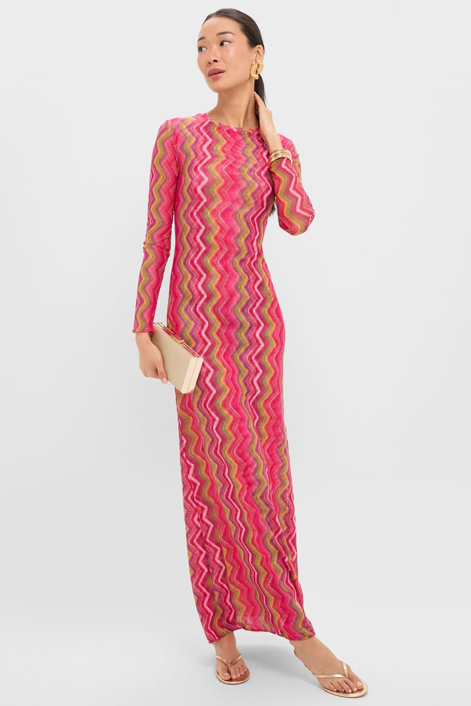 Model wearing the Electric Wave Pink Scarlet Maxi Dress, featuring a classic, colorful zigzag pattern, accessorized with gold jewelry and a beige clutch for an effortless, fun, high-end look.
