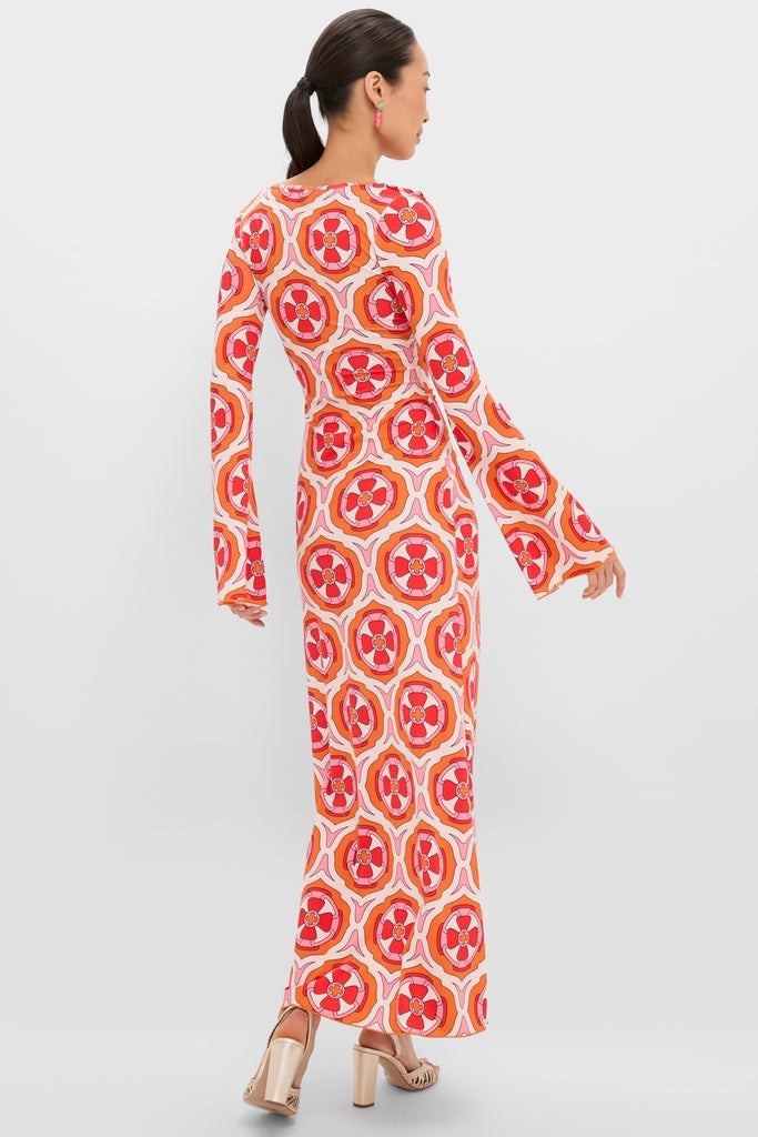 Model in Pink Retro Radiance Diana Bell Maxi Dress featuring a geometric floral motif, long sleeves, and metallic sandals, embodying effortless, high-end style for a fun, classic look.