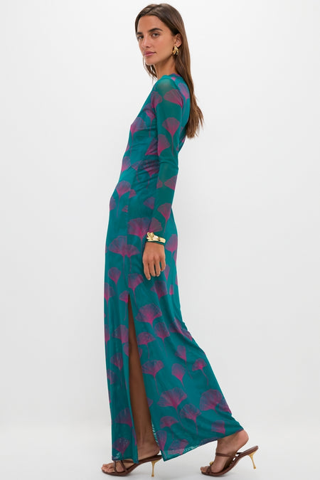 Woman models the Jade Ginkgo Scarlet Maxi Dress, a classic, effortless, and fun teal maxi with a high slit, botanical print, and elegant gold accessories.