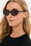 Woman wearing Black Jeanne Sunglasses, featuring small, oval-shaped lenses and a thick frame marked W-GOLDE, embodying classic, effortless style with a high-end touch.