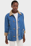 Indigo Barn Jacket modeled, featuring a classic blue denim design with wooden toggle closures, tan corduroy accents, and white stitching, embodying effortless, high-end style.
