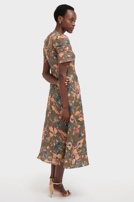 Model in profile in the Olive Floral Casey Dress, showcasing its classic, effortless style with a painterly floral pattern and tiered details, paired with high-end nude-beige sandals.