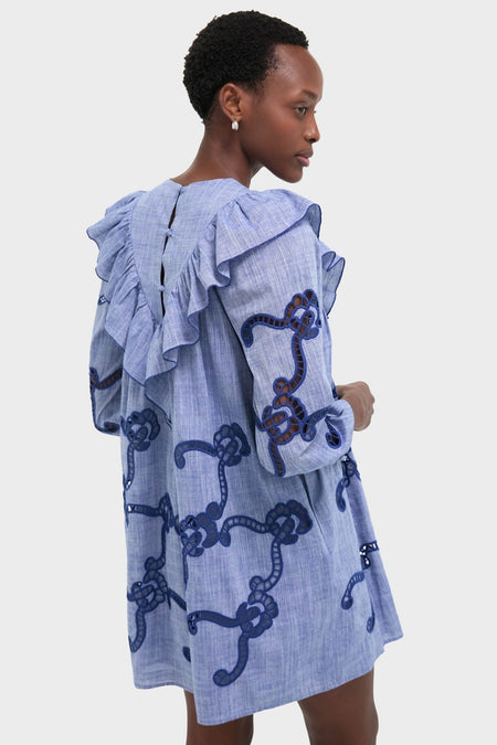 Woman modeling the Seabank Chambray Azalea Dress with a classic, effortless silhouette, featuring ruffled trim and cutwork embroidery, embodying a fun, high-end style.