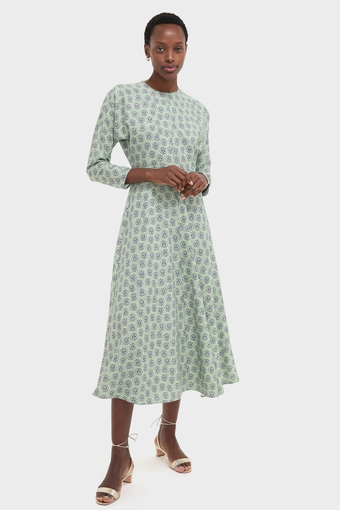 Model wearing the Navy Bird Block Vika Dress, a classic and effortless midi-length dress with a high neckline and flared skirt, styled with fun, high-end strappy sandals.