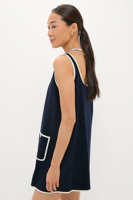 Woman in profile wearing a classic, high-end Navy Mini Terrycloth Button Tank Dress, featuring white-piped trim and a small patch pocket, accessorized effortlessly with a beaded necklace.