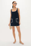 Model in a classic Navy Mini Terrycloth Button Tank Dress with white piping, accessorized with cat-eye sunglasses, layered necklaces, and a straw clutch, embodying effortless, high-end style.
