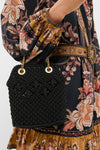 Black Small Macrame Veronica Beard Slouch Bag with gold chain straps, carried stylishly by a model in a bohemian-print dress, epitomizing classic, effortless, high-end fashion.