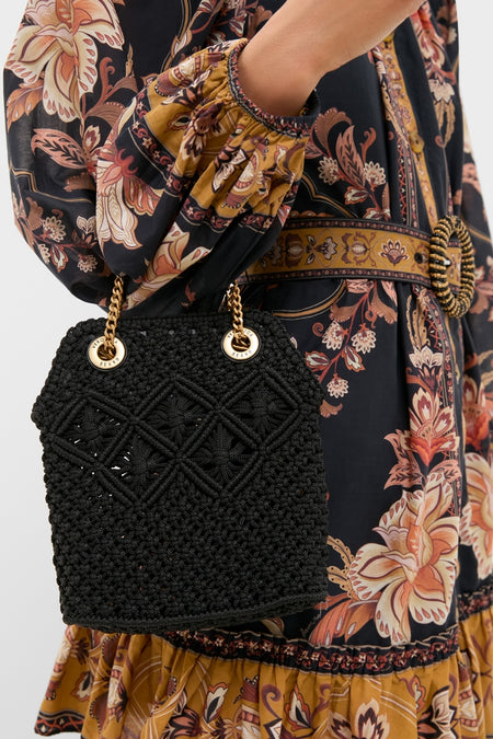Black Small Macrame Veronica Beard Slouch Bag with gold chain straps, carried stylishly by a model in a bohemian-print dress, epitomizing classic, effortless, high-end fashion.