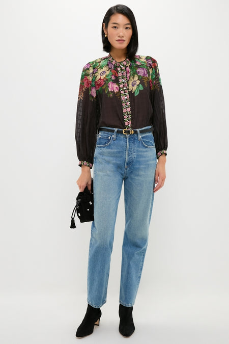 Young woman showcases a classic, high-end look with an effortless Black Small Crystal Stash Bag, complementing her floral blouse and blue jeans ensemble.