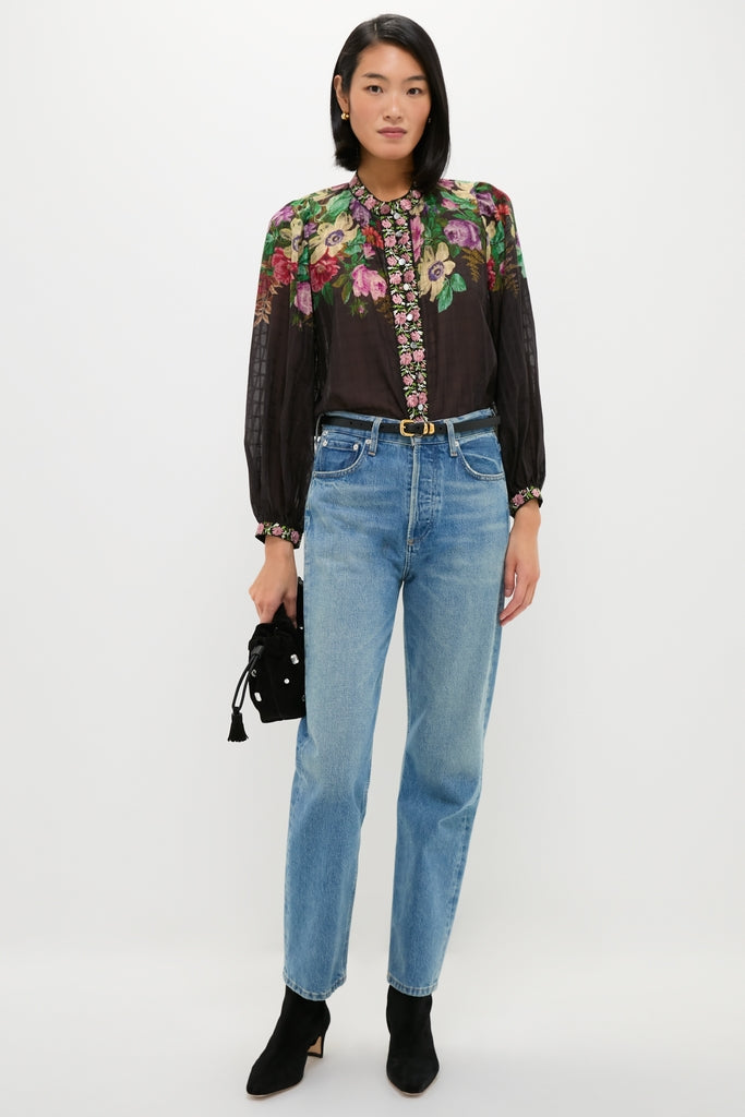 Young woman showcases a classic, high-end look with an effortless Black Small Crystal Stash Bag, complementing her floral blouse and blue jeans ensemble.