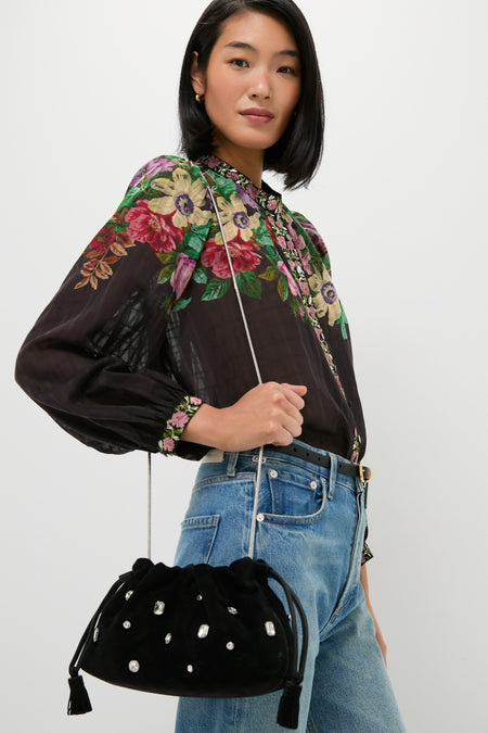 Woman wearing an effortless, high-end Black Small Crystal Stash Bag with rhinestone details and chain strap, complementing a classic floral blouse and jeans ensemble.