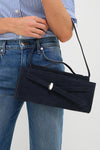 Woman holding the Navy Suede Veronica Beard Dash Clutch, a classic, high-end rectangular bag with a flap closure, silver-tone clasp, and decorative suede belt detail.