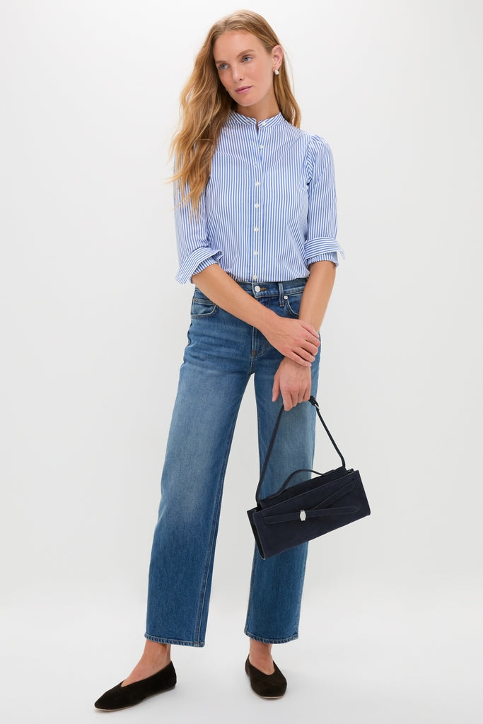 Woman models a classic look with an effortless style, showcasing the high-end Navy Suede Veronica Beard Dash Clutch, paired with a striped blouse and jeans.