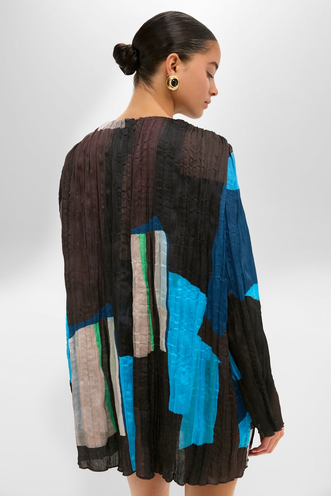 Woman in the Blue Prism Kona Dress with bold abstract panels, showcasing an effortless and classic high-end style, paired with chunky gold-tone hoop earrings.