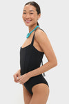 Model wearing the Black Adelaide One Piece, a classic swimsuit with corset-style boning and thin straps, paired effortlessly with a chunky turquoise necklace for a high-end, fun look.