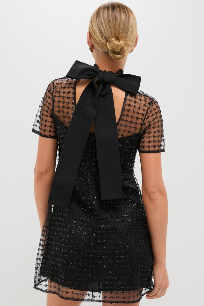 Stardust Onyx Ilana Dress featuring a sheer, star-embellished tulle overlay, classic self-tie bow, and effortless back cut-out, exudes high-end, fun elegance.