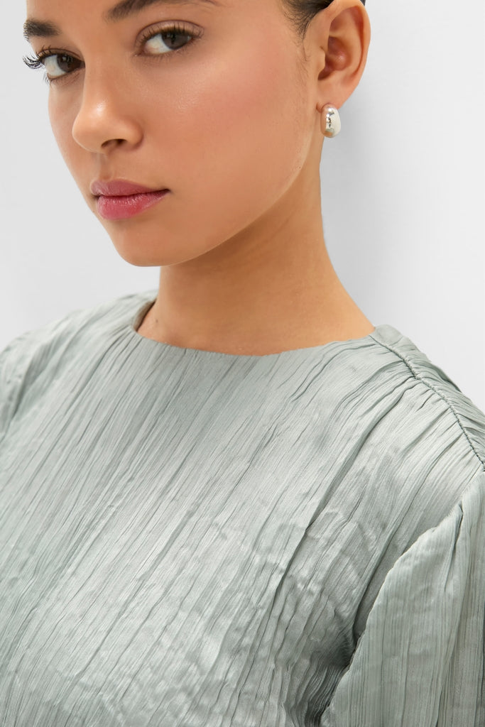 Model wearing Silver Sage Kona Dress with pleated texture, high neckline, and small hoop earring, embodying classic elegance and effortless style.