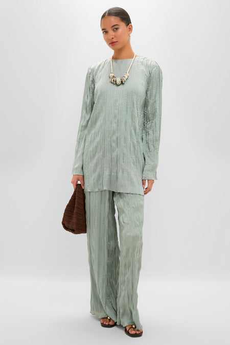 Model in a classic, effortless Silver Sage Kona Dress, a high-end, textured ensemble with a straight silhouette, styled with a chunky necklace and woven handbag.