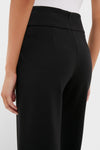Rear view of a model wearing the Black Kalinda Pant, showcasing its high-waisted, wide-leg design and sleek fit with an elegant waistband seam detail.
